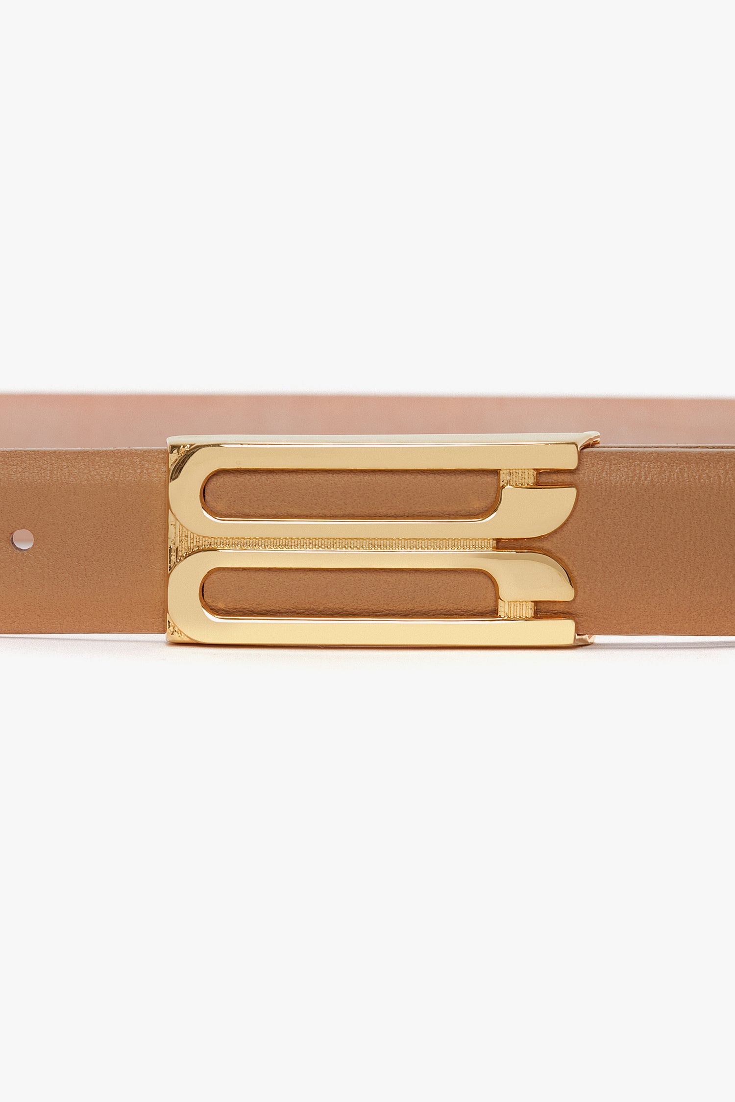 A close-up view of a Victoria Beckham Frame Belt In Camel Leather with luxury gold hardware in the form of a shiny gold buckle.