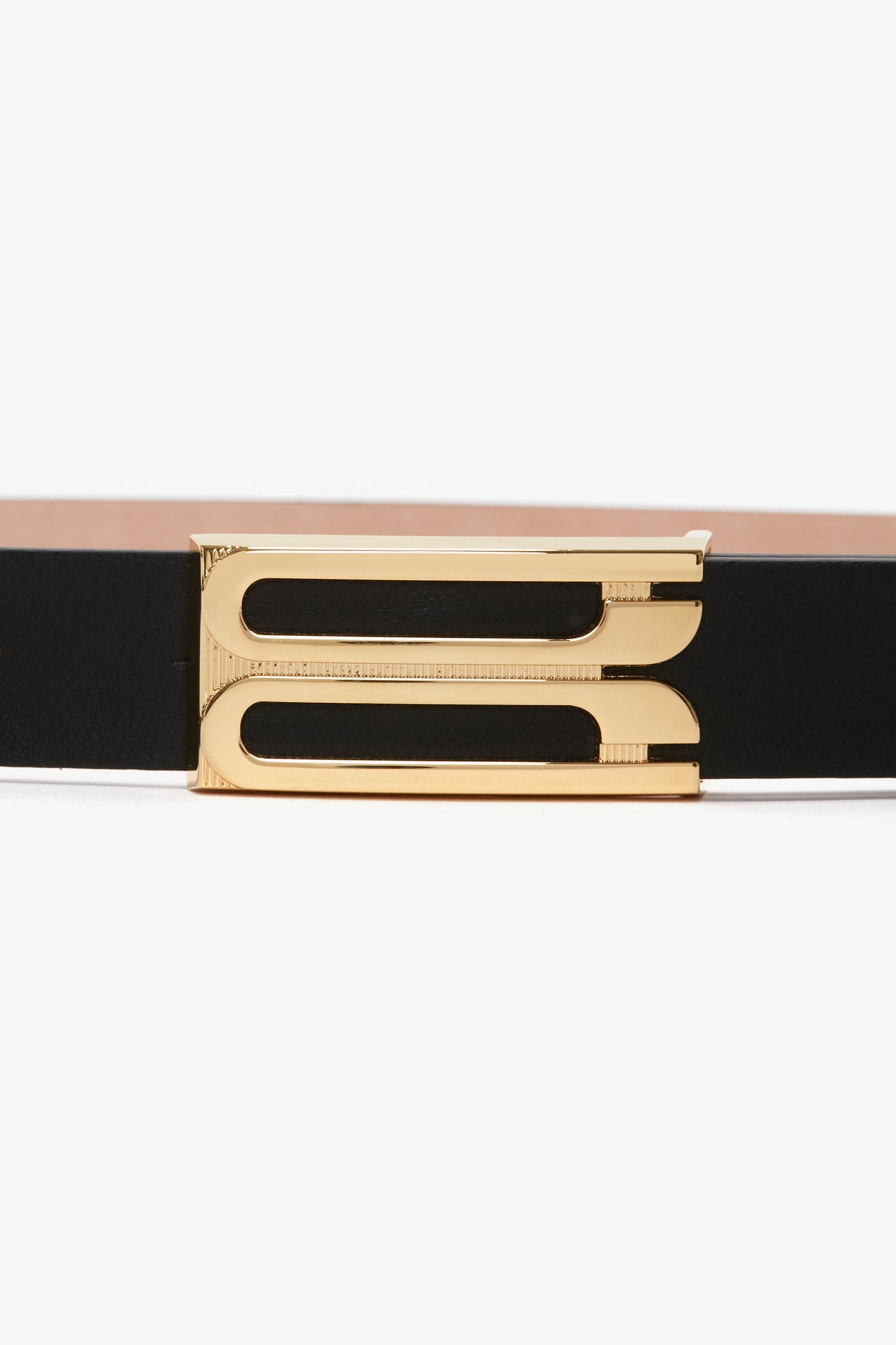 Close-up of a fashion-forward Frame Belt In Black Leather by Victoria Beckham with a gold frame buckle featuring a unique, cutout design.