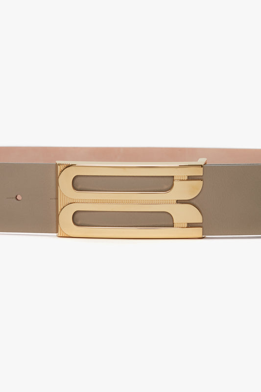 Close-up of an Exclusive Jumbo Frame Belt In Beige Leather with a golden metallic buckle shaped like the letter 'b' by Victoria Beckham.