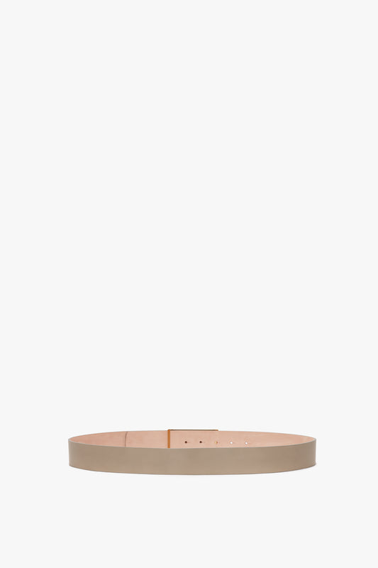 A Victoria Beckham calf leather belt in a light tan color, shown in a coiled position against a white background.