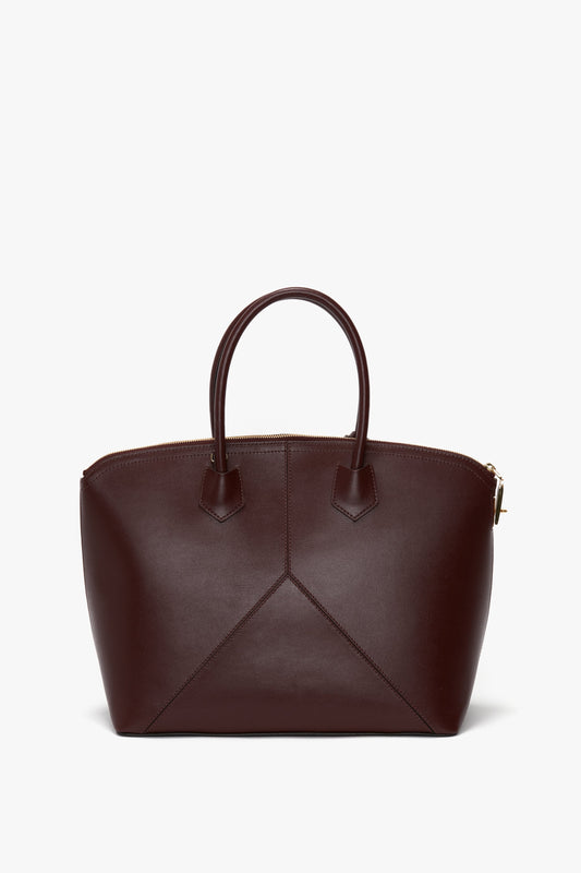 A **Victoria Bag In Burgundy Leather** by **Victoria Beckham** with a structured design, featuring top handles and a padlock closure, set against a white background.
