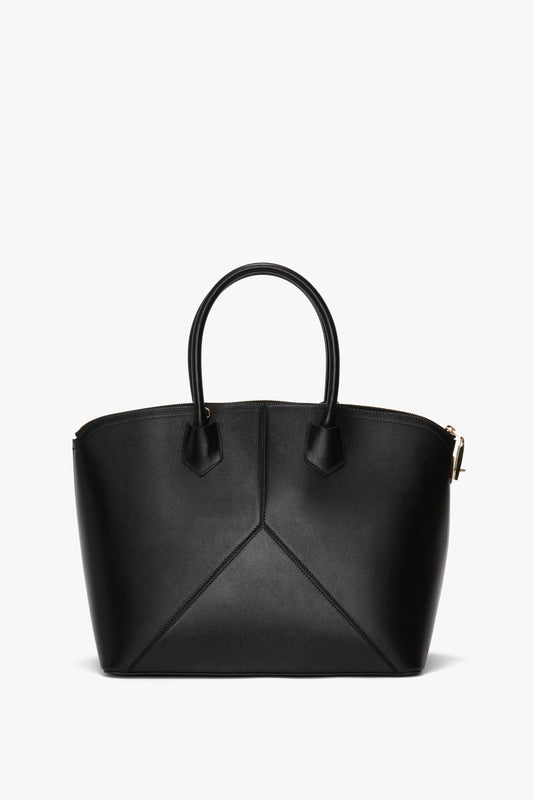 A Victoria Beckham Victoria Bag In Black Leather with a structured design, featuring two top handles, a leather debossed charm, and gold-tone hardware.