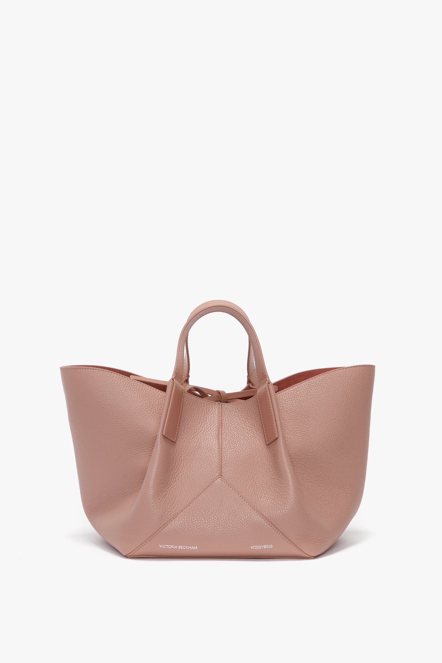 A large, blush-colored calf leather handbag with short handles and a wide base. The W11 Mini Tote Bag In Marshmallow Leather features the brand name "Victoria Beckham" written near the bottom edge.