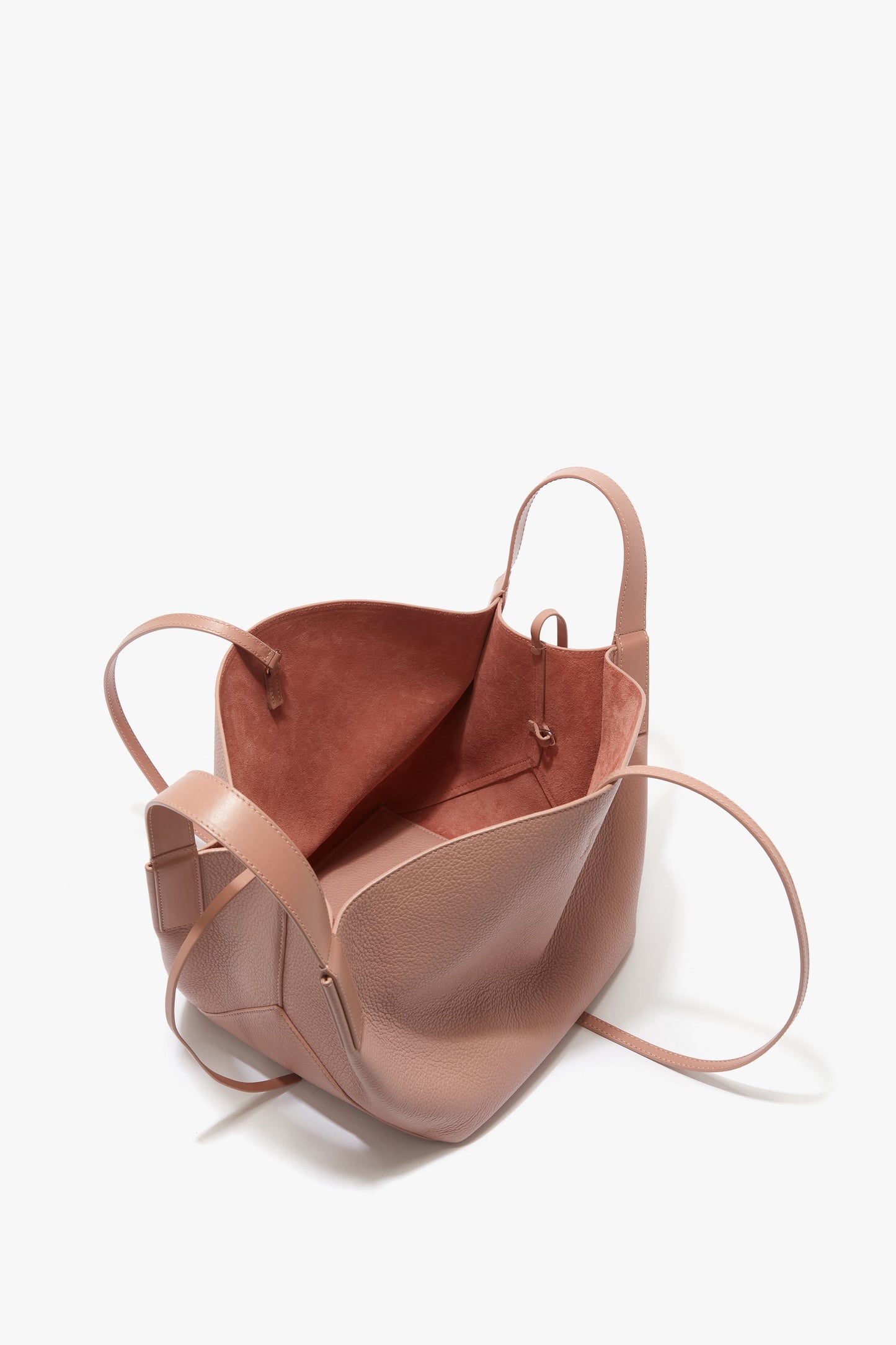 An open, empty W11 Mini Tote Bag In Marshmallow Leather by Victoria Beckham in blush pink calf leather with long, thin shoulder straps and a soft fabric interior.