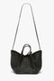 A W11 Mini Tote Bag In Loden Leather by Victoria Beckham with a long strap and short handles, perfect for crossbody wear.