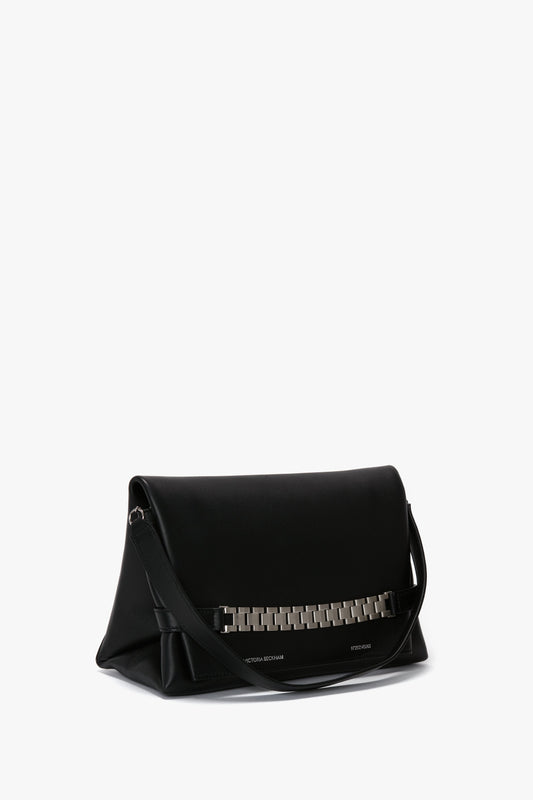 A sleek black leather *Chain Pouch Bag with Brushed Silver Chain In Black Leather* by *Victoria Beckham* with a folded design, a detachable shoulder strap, and a brushed silver chain accent on the front.