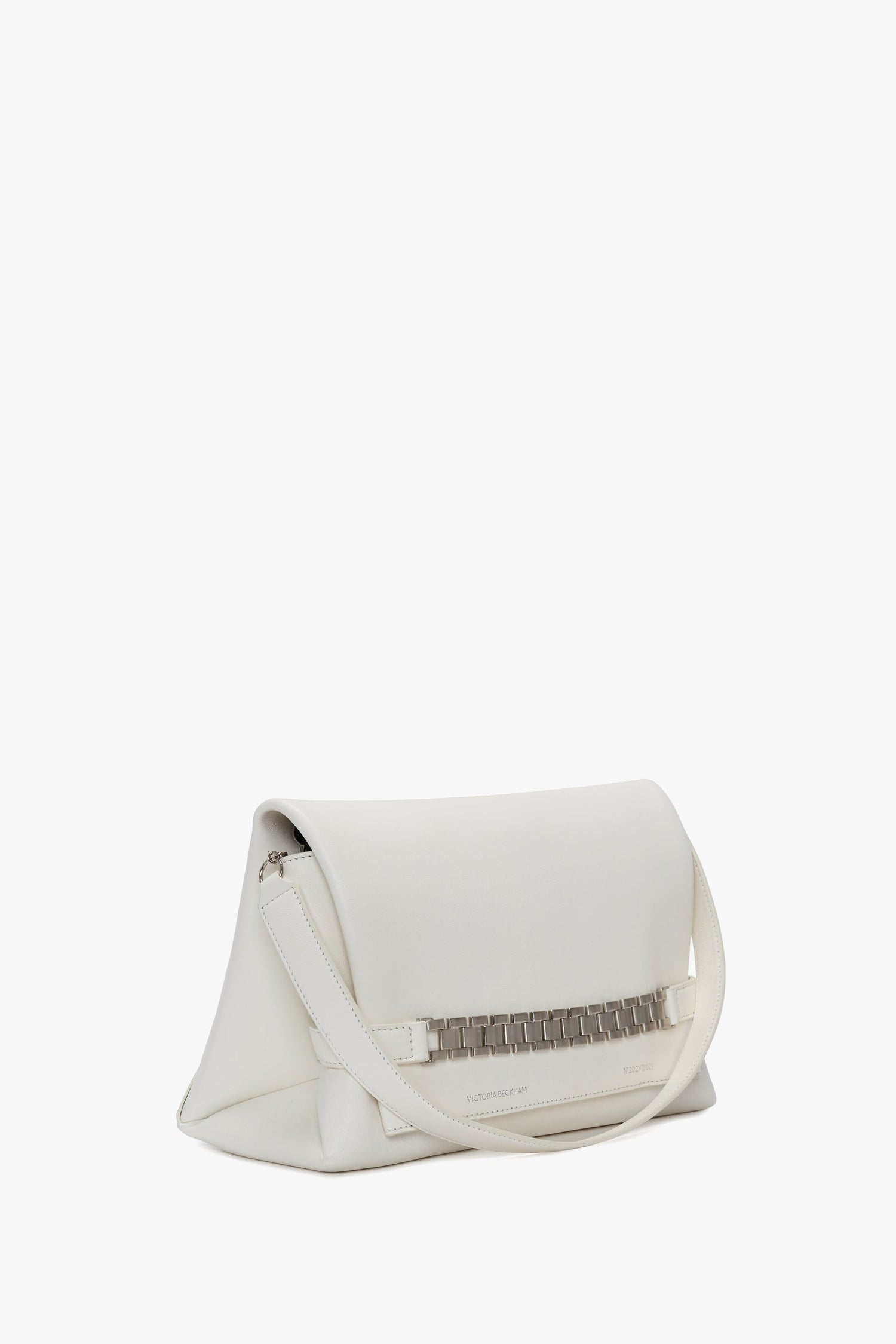 A white, rectangular Chain Pouch Bag with Brushed Silver Chain In White with a fold-over flap, silver Victoria Beckham branding, and a thin shoulder strap. The handbag features a chic metal accent on the front and comes with a detachable strap for versatile styling.