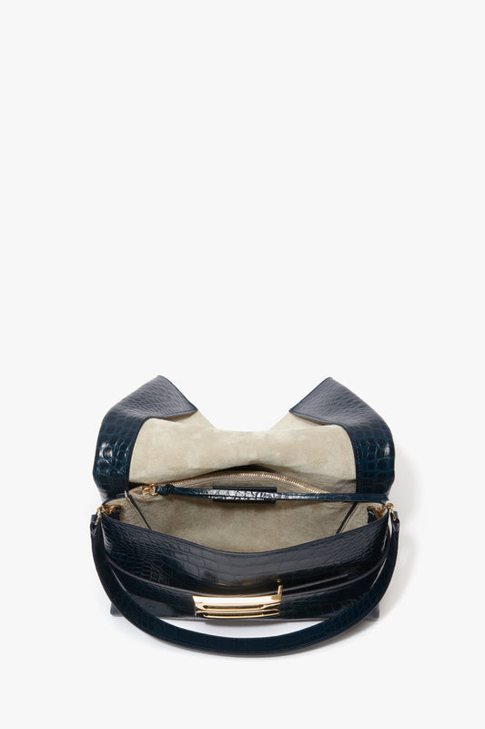 A B Pouch Bag In Croc Effect Midnight Blue Leather by Victoria Beckham with an open top revealing a beige interior, a central zippered compartment, and elegant calf leather finish.