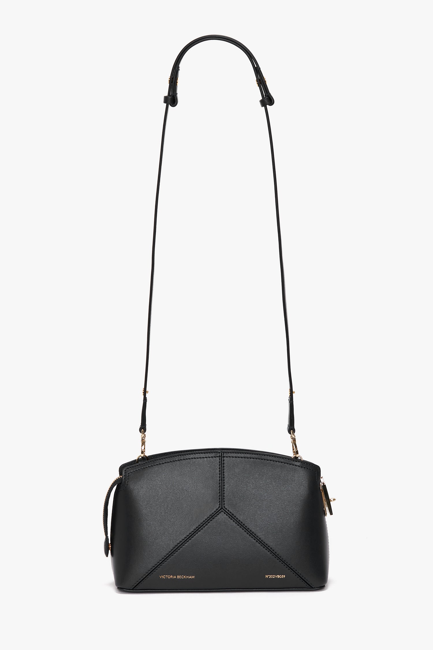 The **Victoria Beckham Victoria Crossbody Bag In Black Leather** is a black leather bag featuring textured calf leather with a geometric design, gold hardware, and an adjustable strap.