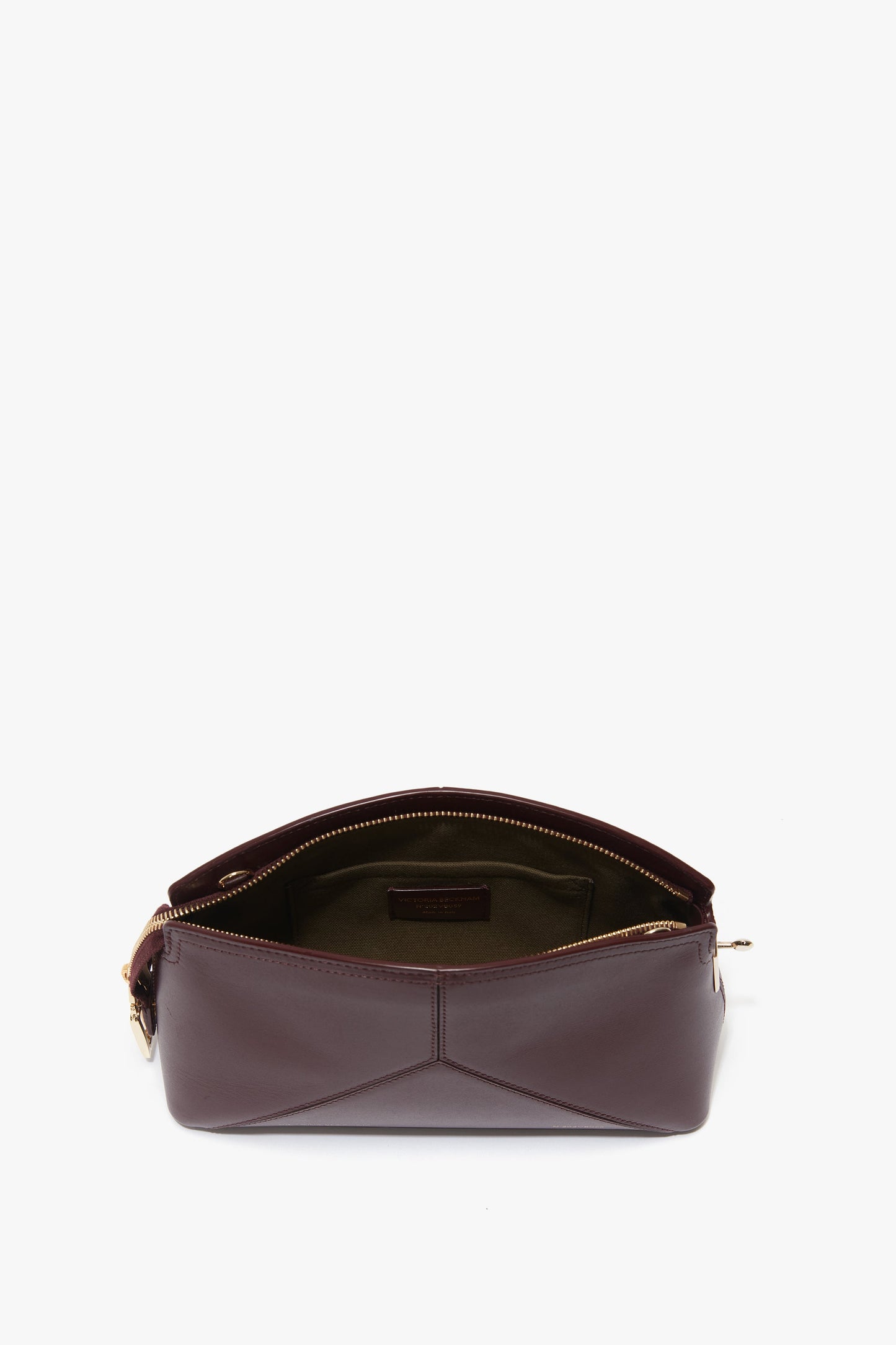 Brown leather Victoria Beckham Victoria Crossbody Bag In Burgundy Leather with the top unzipped, revealing an inner compartment. The bag has a minimalist design with clean lines and no visible brand logos.