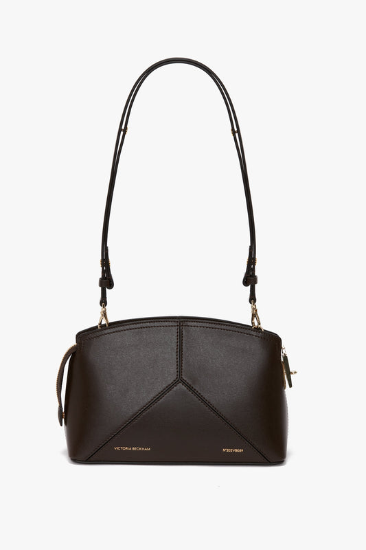 A small, brown, calf leather handbag with gold zippers and accents, featuring an adjustable shoulder strap and the name "Victoria Beckham" embossed on the front.