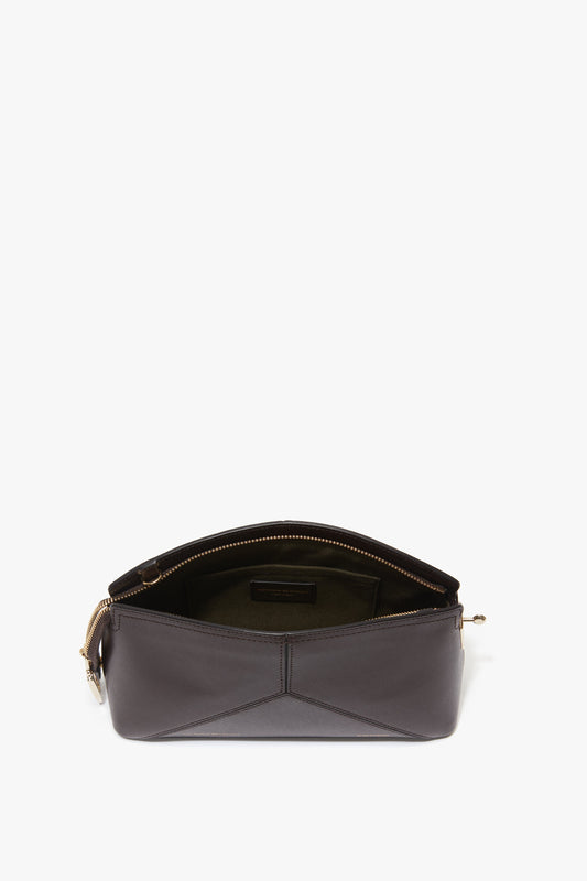 The Victoria Beckham Exclusive Victoria Crossbody Bag In Brown Leather is a black calf leather handbag with a gold zipper partially opened, revealing an olive green interior and an inner pocket. An adjustable strap adds to its versatility and timeless elegance.