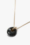 Elegant Victoria Beckham Exclusive Resin Pendant Necklace In Light Gold-Black featuring a black stone pendant with white streaks and a gold accent loop, crafted in Italy.