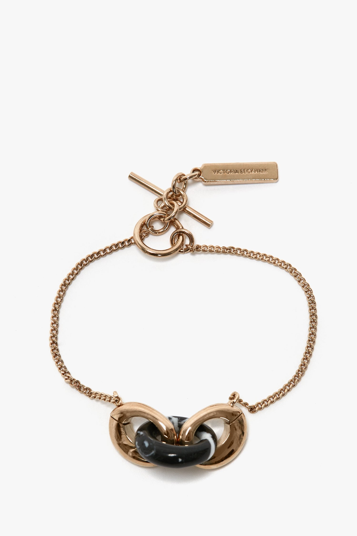 A 100% brass bracelet in Light Gold/Black with a black central link, featuring a toggle clasp and a rectangular resin charm. Introducing the Exclusive Resin Charm Bracelet In Light Gold-Black by Victoria Beckham.