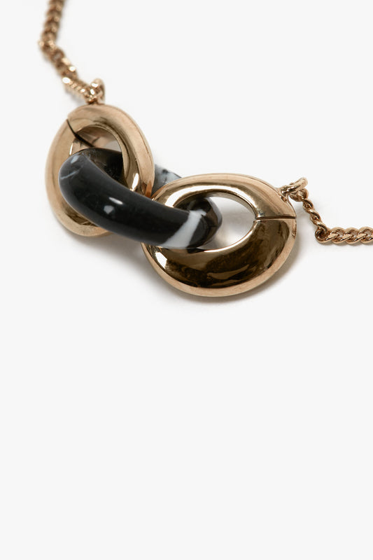 A close-up image of a Victoria Beckham Exclusive Resin Charm Bracelet In Light Gold-Black featuring intertwined Light Gold/Black oval links on a 100% brass chain, set against a plain white background.