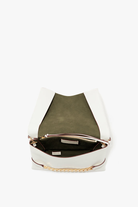 A white Chain Pouch Bag with Strap In White Leather by Victoria Beckham with an open top view showing a green interior lining, a zippered pocket, and a small label inside. It features a detachable strap for versatility.