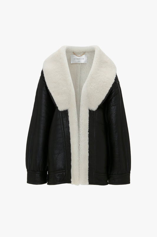 A Victoria Beckham Shearling Coat In Monochrome with a large white shearling collar and interior lining, boasting an oversized silhouette, displayed against a plain white background.