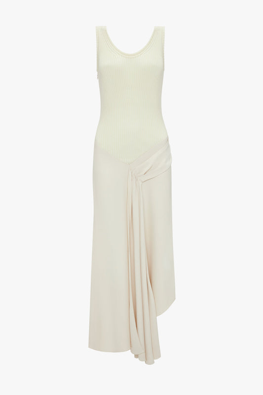 The Victoria Beckham Sleeveless Tie Detail Dress In Cream features a fitted ribbed bodice, a pleated draped detail, and an asymmetric hemline.