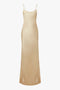 A full-length, sleeveless beige silk dress with thin straps and a smooth texture, this Exclusive Floor-Length Cami Dress In Gold by Victoria Beckham exudes timeless elegance.