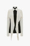 A Victoria Beckham Oversized Bow Detail Blouse in Vanilla with a cape-style drape, button-front closure, and a collared neckline.