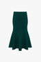 A dark green, high-waisted Victoria Beckham VB Body Flared Skirt In Lurex Green with a smooth texture, crafted from compact knitwear.