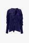 A dark blue, long-sleeved Tie Detail Ruffle Blouse In Ultraviolet by Victoria Beckham with layered ruffles and a tied neckline is displayed against a plain white background.