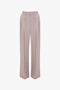 A pair of Double Pleat Trouser In Rose Quartz by Victoria Beckham is displayed against a white background, showcasing a directional silhouette.