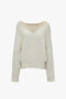 A cream-colored, lambswool V-Neck Jumper In Natural with a cable-knit design and long sleeves by Victoria Beckham, featuring a slightly oversized fit.