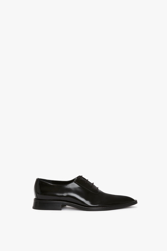 Victoria Beckham Pointy Toe Flat Lace Up In Black Brushed Leather with a slight heel, polished finish, and four lace eyelets, displayed on a white background.