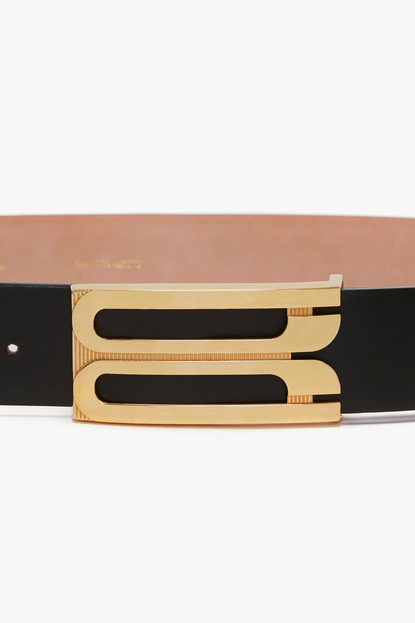 Close-up of the Victoria Beckham Jumbo Frame Belt In Black Leather, featuring a unique rectangular gold buckle with two parallel cut-out designs.