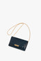 A dark blue, embossed croc leather **Wallet On Chain In Midnight Croc-Effect Leather** with a gold metal chain strap and a rectangular gold clasp, evocative of **Victoria Beckham** leather goods, placed on a white background.