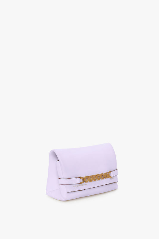 A small, lilac-colored clutch bag featuring gold-tone hardware and a simple, modern design with a detachable strap against a plain white background by Victoria Beckham.