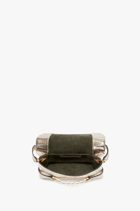 A small, open handbag with a metallic silver bottom, green suede top, and a gold-tone chain strap, viewed from above on a white background. 
Product Name: Mini Chain Pouch With Long Strap In Gold Leather
Brand Name: Victoria Beckham
