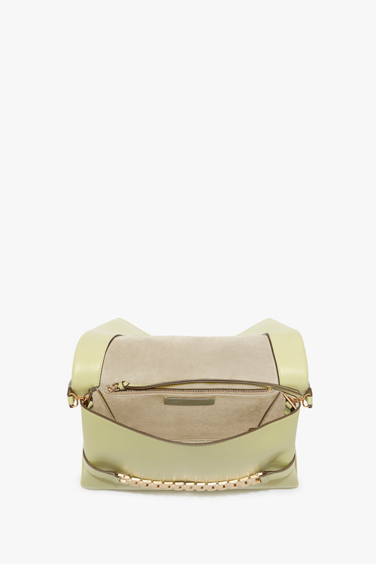 A light green Chain Pouch Bag With Strap In Avocado Leather with a zipper closure and a suede-textured front pocket, featuring a gold chain detail for a touch of elegance. This versatile Victoria Beckham bag combines style and functionality seamlessly.