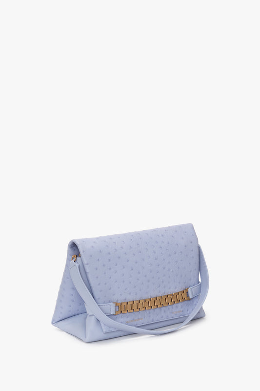 A pale blue embossed ostrich-effect leather Chain Pouch with Strap in Frost Ostrich-Effect Leather, from Victoria Beckham, with a gold bar clasp, positioned slightly open against a white background.