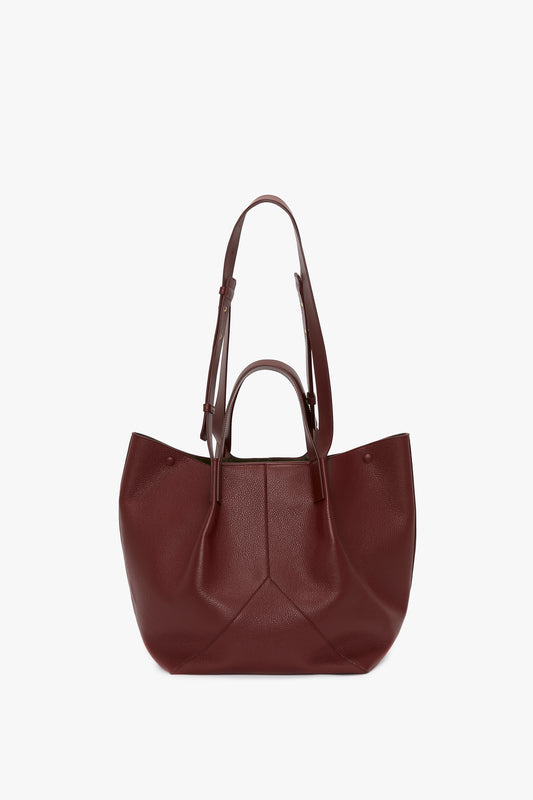 A W11 Medium Tote Bag In Burgundy Leather by Victoria Beckham, featuring two sets of handles: a short pair and a longer adjustable shoulder strap for versatile styling.