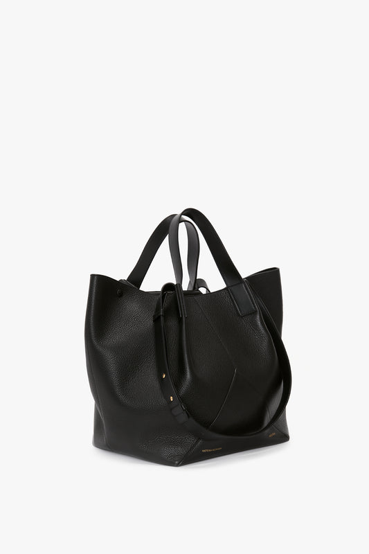A large W11 Medium Tote Bag In Black Leather by Victoria Beckham, featuring two handles and an additional small pouch attached to the front, exemplifies the finest in leather goods.