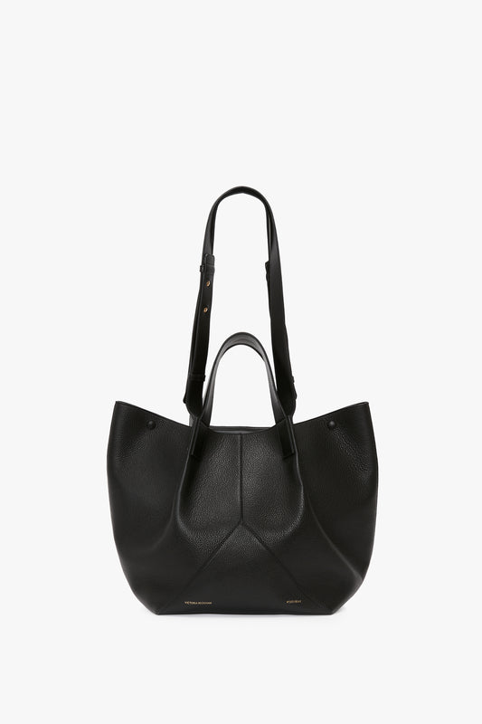 Victoria Beckham's W11 Medium Tote Bag In Black Leather features two short handles and an adjustable shoulder strap, making it a versatile piece among luxury leather goods.