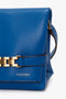 Close-up of a Mini Chain Pouch Bag With Long Strap In Sapphire Blue featuring a gold chain detail and a text label "N°202VB011" on the front by Victoria Beckham.