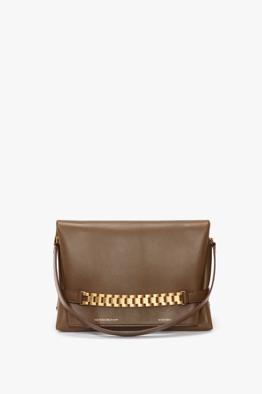 A chic brown Nappa leather shoulder bag with a gold chain detail across the front and a single detachable strap, resembling the stylish elegance of a Chain Pouch Bag With Strap In Khaki Leather by Victoria Beckham.