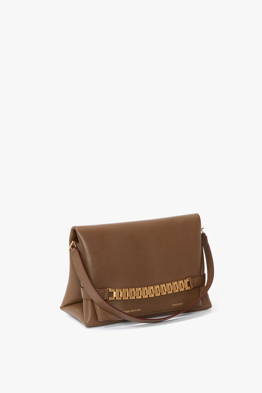 Chain Pouch Bag With Strap In Khaki Leather by Victoria Beckham with a gold chain detail on the front flap and a single detachable brown shoulder strap.