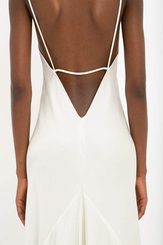 Back view of a person wearing a sleeveless, backless Victoria Beckham Floor-Length Cami Dress In Ivory with thin shoulder straps, echoing the timeless elegance of 90s fashion.