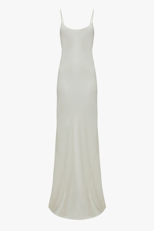 A Floor-Length Cami Dress In Ivory from Victoria Beckham with thin spaghetti straps and a slightly flared hem, evoking a touch of 90s fashion.