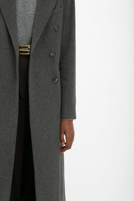 A person is wearing a Victoria Beckham Tailored Slim Coat In Grey Melange, with a visible gray sweater and dark pants. Only part of the person's torso and right arm are visible, showcasing a flattering silhouette reminiscent of classic military menswear.