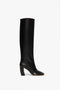 Black knee-high heeled leather Capri Rise Boot 115mm in Black by Victoria Beckham with a rounded toe, crafted from sleek black calf leather and shown in a side profile view against a plain white background.