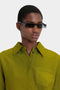 Person wearing a green shirt and Mini Visor Sunglasses In Black-Green from Victoria Beckham, looking straight ahead.