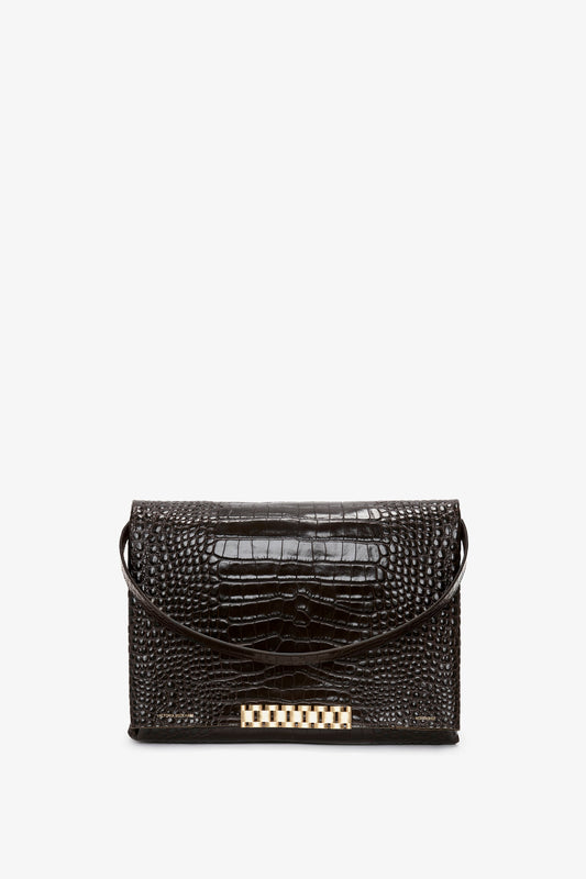 A Jumbo Chain Pouch Bag In Chocolate Croc-Effect Leather with a gold-tone rectangular clasp on the front and a thin strap for carrying. This elegant piece by Victoria Beckham offers versatile styling, making it perfect for any occasion.