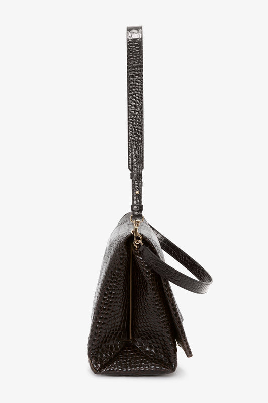 Side view of a versatile styling, black, textured leather handbag with a single strap and gold-tone hardware, the **Jumbo Chain Pouch Bag In Chocolate Croc-Effect Leather** by **Victoria Beckham**.