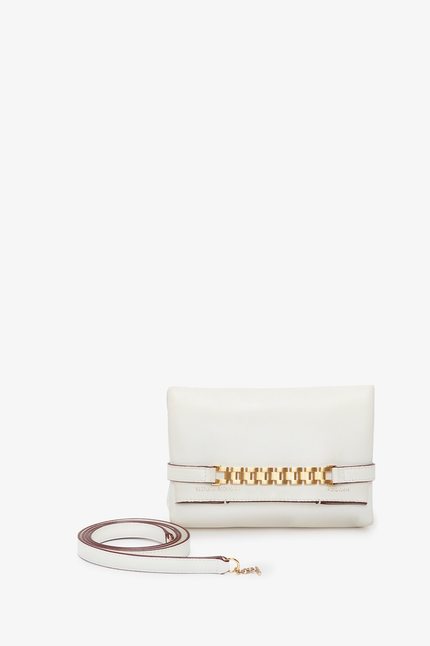 A Mini Chain Pouch Bag With Long Strap In White Leather by Victoria Beckham, this white leather clutch with a gold chain detail on the front and a removable strap lies beside it against a pristine white background.