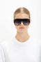 Woman with slicked-back hair wearing Victoria Beckham's Layered Mask Sunglasses In Black Gradient and a white crew-neck shirt against a plain white background.